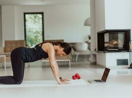 giovane bellissimo femmina esercizio, allungamento e praticando yoga con allenatore attraverso video chiamata conferenza nel luminosa soleggiato Casa. salutare stile di vita, benessere e consapevolezza concetto. foto