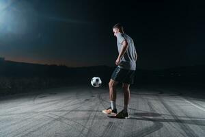 ritratto di un' giovane bello calcio giocatore uomo su un' strada giocando con un' calcio sfera. foto