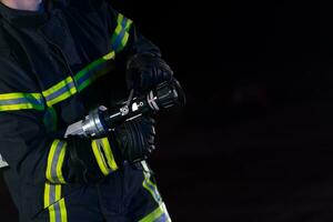 i vigili del fuoco uso un' acqua tubo flessibile per eliminare un' fuoco rischio. squadra di pompiere nel il pericoloso salvare missione. foto