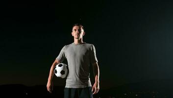 ritratto di un' giovane bello calcio giocatore uomo su un' strada giocando con un' calcio sfera. foto