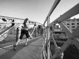 donna che fa jogging attraverso il ponte al mattino soleggiato foto