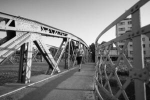 donna che fa jogging attraverso il ponte al mattino soleggiato foto