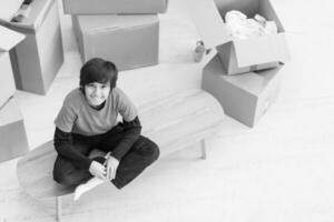 ragazzo seduto sul tavolo con scatole di cartone intorno a lui vista dall'alto foto
