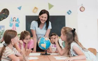 femmina insegnante con bambini nel geografia classe guardare a globo. lato Visualizza di gruppo di diverso contento scuola bambini con globo nel aula a scuola. foto