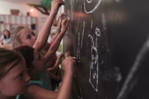 bambini Scrivi e disegnare su il lavagna nel elementare scuola mentre apprendimento il le basi di formazione scolastica foto