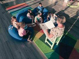 lettura tempo nel elementare scuola o asilo, insegnante lettura un' libro per bambini nel elementare scuola o asilo nido. selettivo messa a fuoco foto