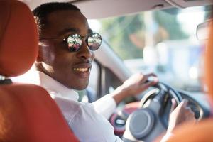 felice afroamericano alla guida di un'auto, in estate