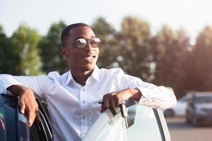 felice afroamericano accanto a un'auto in estate foto