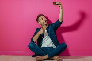 ritratto di un' contento uomo utilizzando smartphone isolato al di sopra di rosa sfondo. foto