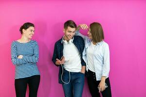 gruppo di giovane persone nel moderno Abiti in posa e avendo divertimento isolato nel davanti di rosa sfondo foto