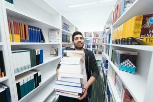 alunno Tenere lotto di libri nel scuola biblioteca foto