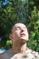 uomo lavare testa sotto doccia con caduta acqua foto