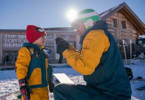 padre preparazione il suo poco figlio per il primo tempo su un' Snowboard foto