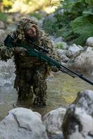 un' militare uomo o softair giocatore nel un' camuffare completo da uomo Sneaking il fiume e obiettivi a partire dal un' cecchino fucile per il lato o per obbiettivo. foto