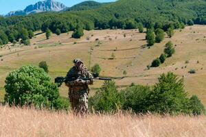 esercito soldato Tenere un' cecchino fucile con scopo e a piedi nel il foresta. guerra, esercito, tecnologia e persone concetto. foto