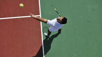 il giovane gioca a tennis all'aperto foto