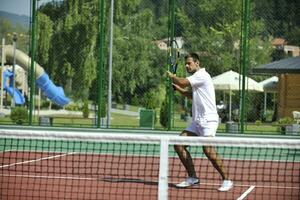 il giovane gioca a tennis all'aperto foto