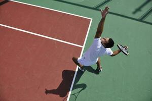 il giovane gioca a tennis all'aperto foto