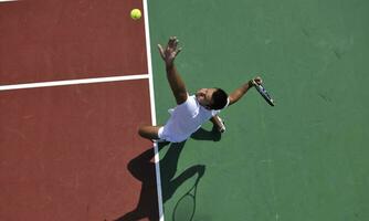 il giovane gioca a tennis all'aperto foto