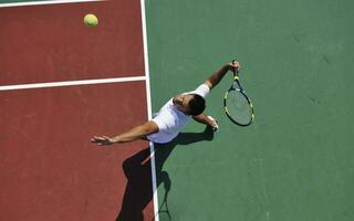 il giovane gioca a tennis all'aperto foto