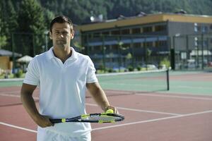 il giovane gioca a tennis all'aperto foto