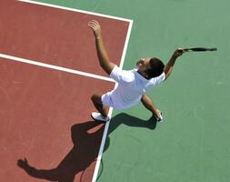 il giovane gioca a tennis all'aperto foto