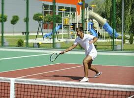 il giovane gioca a tennis all'aperto foto