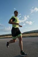 atleta di triathlon che corre durante l'allenamento mattutino foto