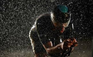 Triathlon atleta equitazione bicicletta veloce su piovoso notte foto
