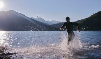 atleta di triathlon che inizia l'allenamento di nuoto sul lago foto