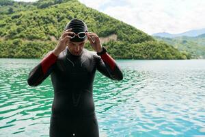 atleta di triathlon che si prepara per l'allenamento di nuoto sul lago foto