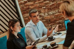 contento uomini d'affari sorridente allegramente durante un' incontro nel un' caffè negozio. gruppo di riuscito attività commerciale professionisti Lavorando come un' squadra nel un' multiculturale posto di lavoro. foto