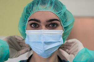 il femmina animale chirurgo o veterinario mette su un' medico viso maschera. medico è preparazione per chirurgia nel il operazione camera. medicina e assistenza sanitaria foto