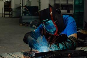 saldatore professionista dell'industria pesante che lavora all'interno della fabbrica, indossa il casco e inizia a saldare. messa a fuoco selettiva foto