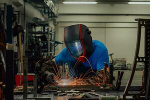 saldatore professionista dell'industria pesante che lavora all'interno della fabbrica, indossa il casco e inizia a saldare. messa a fuoco selettiva foto