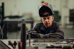 saldatore professionista dell'industria pesante che lavora all'interno della fabbrica, indossa il casco e inizia a saldare. messa a fuoco selettiva foto