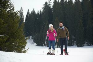 coppia divertendosi e camminando con le racchette da neve foto