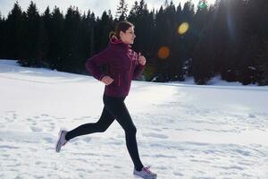 giovane donna jogging all'aperto su neve nel foresta foto