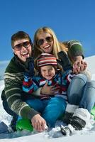 famiglia avendo divertimento su fresco neve a inverno foto