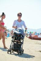 madre a piedi su spiaggia e spingere bambino carrozza foto