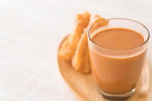 stecco di pasta fritto con tè al latte su legno foto