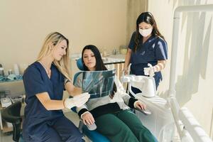 latina femmina dentista spiegando dente raggi x per un' paziente. foto