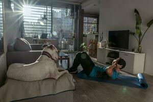 atletico uomo formazione a casa mentre il suo cane sembra a lui. foto