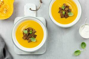 di stagione autunno arrostito zucca e carota la minestra con crema e segale pane crostini su un' leggero calcestruzzo sfondo. superiore Visualizza. foto