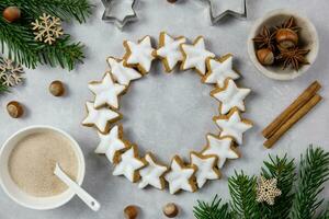 Natale tradizionale Tedesco ghirlanda biscotti, cannella stelle con Nocciole, decorazione e albero rami su un' leggero calcestruzzo sfondo. superiore Visualizza. foto