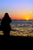 silhouette di persone e il mare al tramonto foto