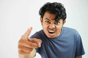 arrabbiato aggressivo giovane asiatico uomo indossare t camicia Marina Militare colore urlando su forte con feroce espressione e punto con un' dito frustrato foto