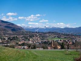 vista panoramica sul lago, montagne innevate e un piccolo paese foto