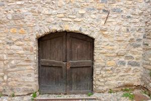 ha chiuso la porta di legno ad arco in un muro fatto di pezzi di pietre di roccia foto