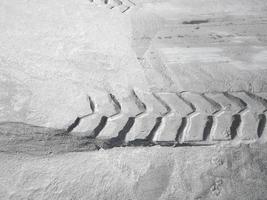le stampe del pneumatico del trattore sulla sabbia bianca in fabbrica, copia spazio